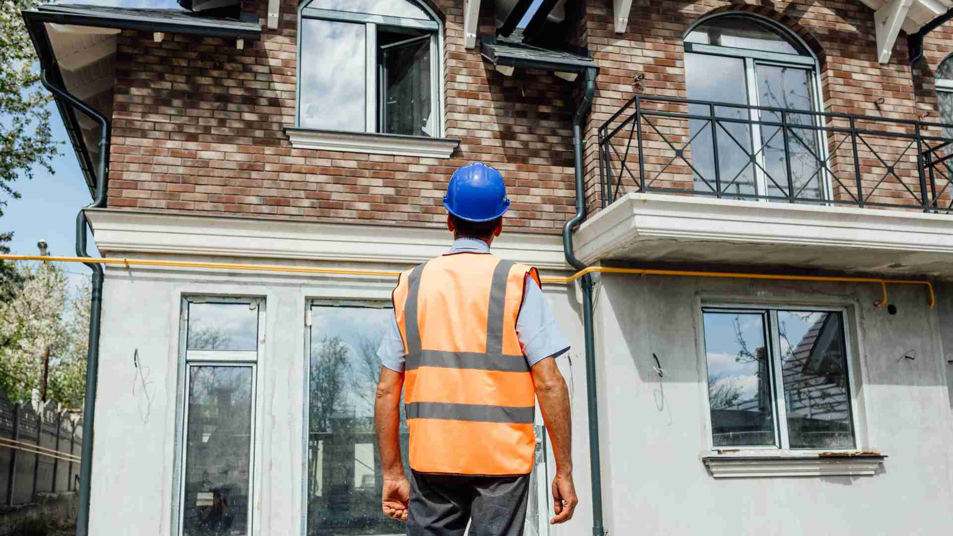 Photo d'un ouvrier face à une maison