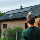 Photo d'un homme et de sa fille qui regarde leur maison avec des panneaux photovoltaïques