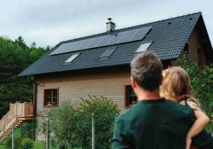 Photo d'un homme et de sa fille qui regarde leur maison avec des panneaux photovoltaïques