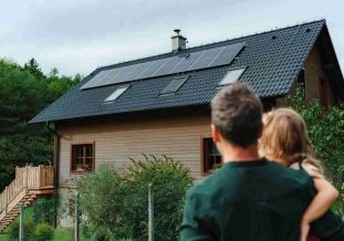 Photo d'un homme et de sa fille qui regarde leur maison avec des panneaux photovoltaïques